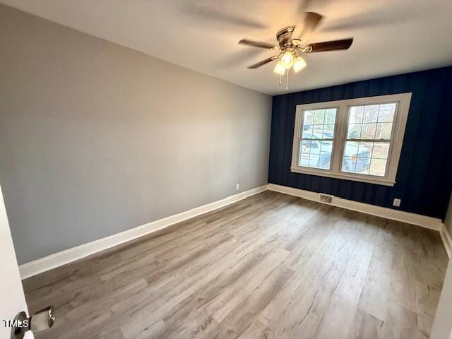 unfurnished room with dark wood finished floors, a ceiling fan, and baseboards