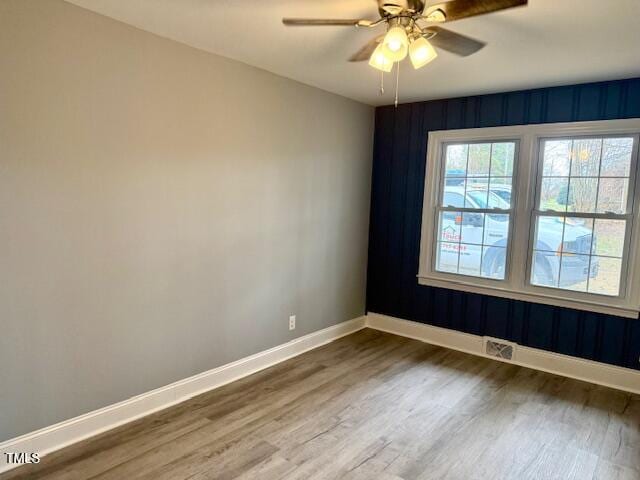 empty room featuring dark wood-style floors, visible vents, ceiling fan, and baseboards