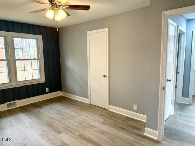 unfurnished room featuring ceiling fan, visible vents, baseboards, and wood finished floors