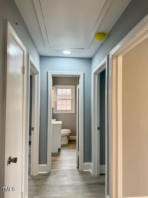 corridor with attic access, baseboards, and wood finished floors