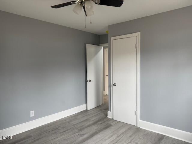 unfurnished bedroom with a ceiling fan, wood finished floors, and baseboards