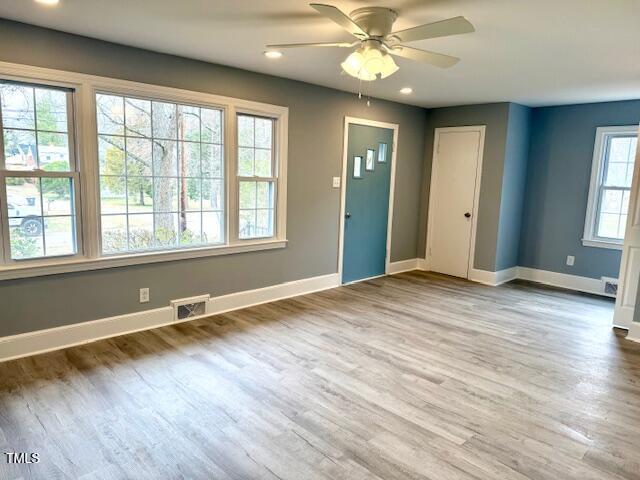 interior space with wood finished floors, baseboards, visible vents, and ceiling fan