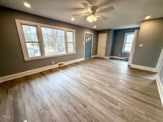 interior space featuring visible vents, a ceiling fan, baseboards, and wood finished floors