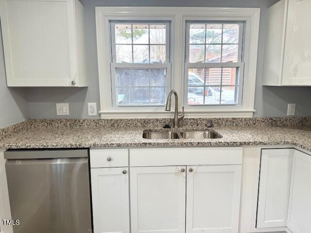 kitchen with a sink, light stone countertops, white cabinetry, and stainless steel dishwasher