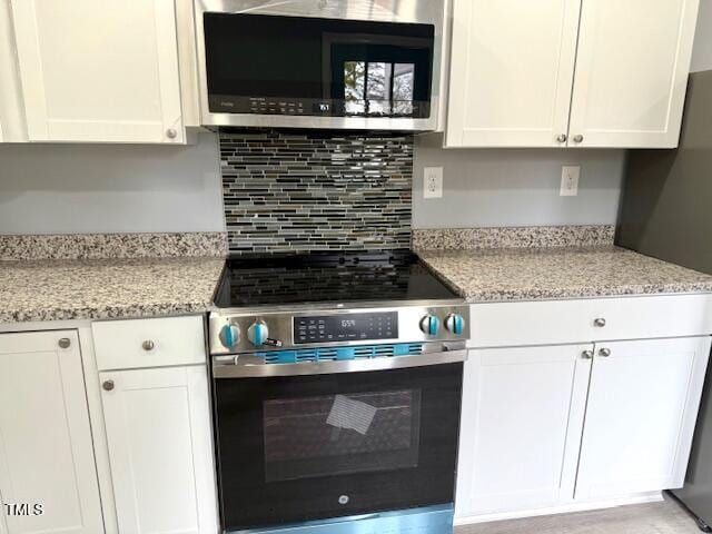 kitchen featuring light stone counters, decorative backsplash, white cabinetry, and stainless steel appliances