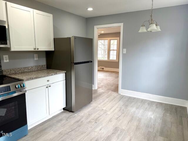 kitchen featuring a notable chandelier, appliances with stainless steel finishes, white cabinetry, and light wood-type flooring