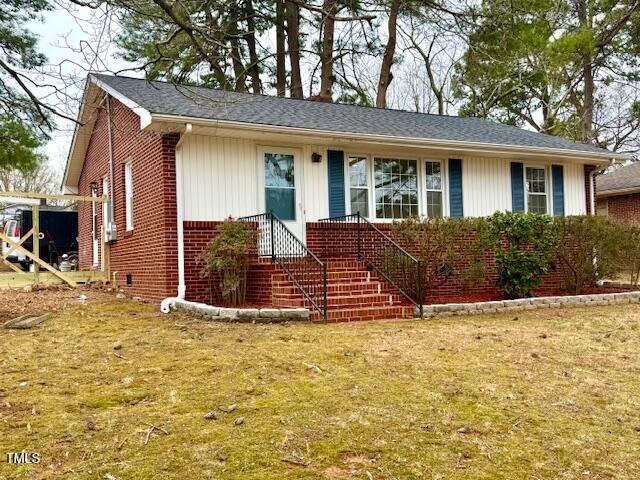 ranch-style house featuring brick siding and a front yard