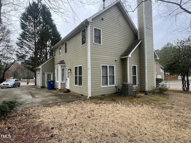 rear view of property featuring crawl space, a patio, a chimney, and central air condition unit