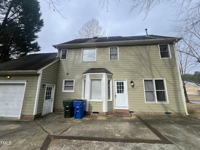 rear view of property with a garage, crawl space, and entry steps