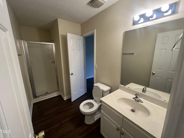 full bathroom featuring a textured ceiling, toilet, wood finished floors, vanity, and a shower stall