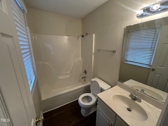 bathroom with a textured ceiling, bathtub / shower combination, toilet, wood finished floors, and vanity