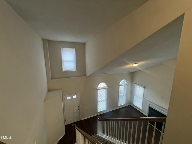 interior space featuring a fireplace, a towering ceiling, baseboards, and wood finished floors