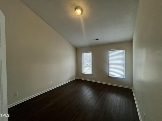 spare room with dark wood-style floors, visible vents, and baseboards