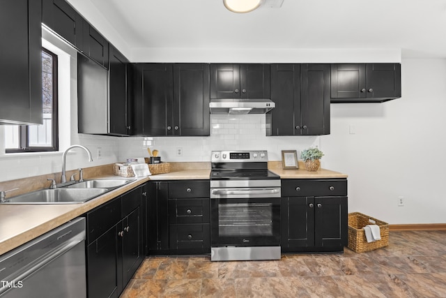 kitchen featuring appliances with stainless steel finishes, backsplash, dark cabinets, under cabinet range hood, and a sink