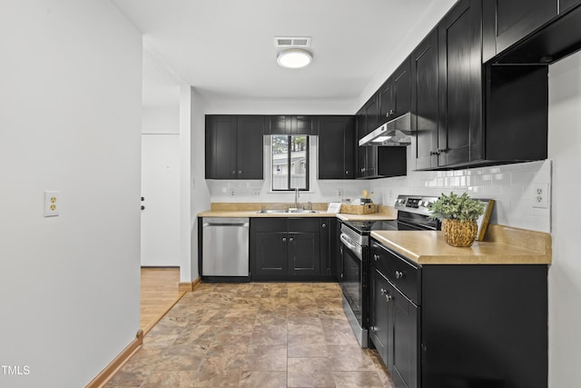 kitchen with appliances with stainless steel finishes, under cabinet range hood, a sink, and dark cabinets