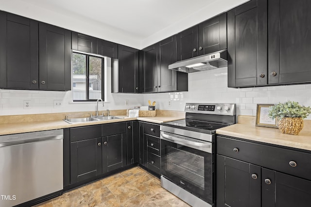 kitchen with under cabinet range hood, dark cabinets, stainless steel appliances, and a sink