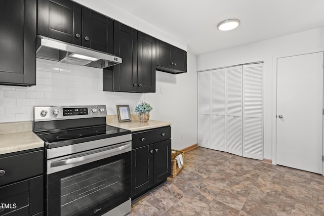 kitchen featuring under cabinet range hood, stainless steel electric range oven, backsplash, and dark cabinetry