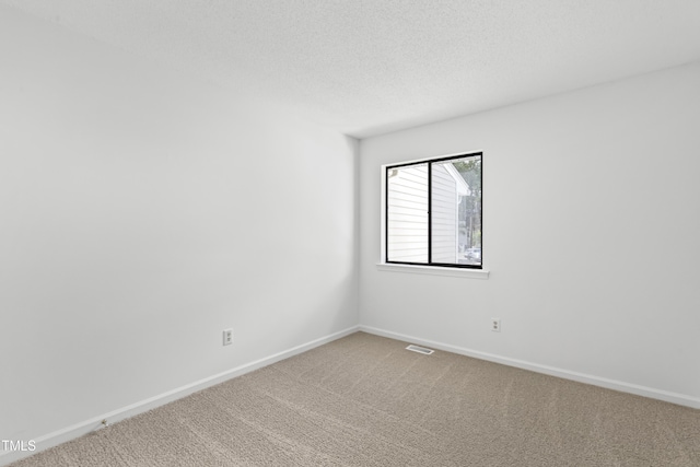 carpeted spare room with a textured ceiling, visible vents, and baseboards