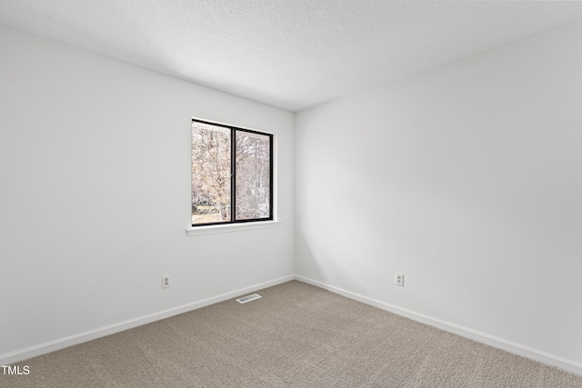 empty room with baseboards, carpet flooring, visible vents, and a textured ceiling