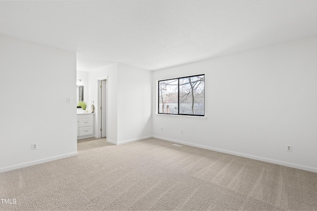 spare room with baseboards and light colored carpet