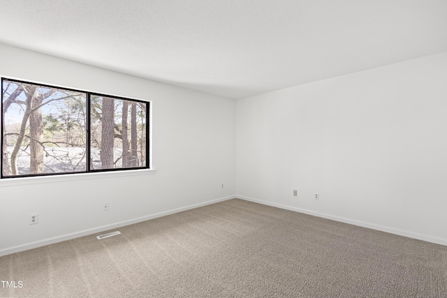 spare room featuring carpet, visible vents, and baseboards