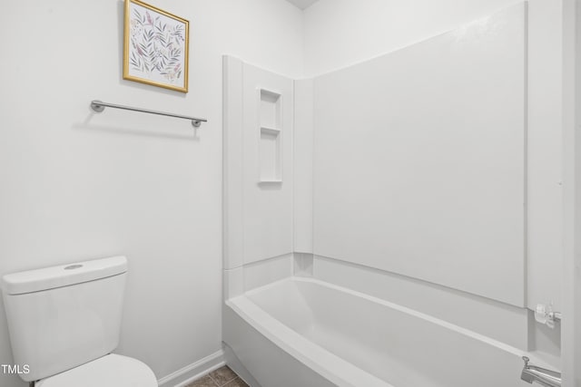 bathroom featuring baseboards, shower / tub combination, and toilet