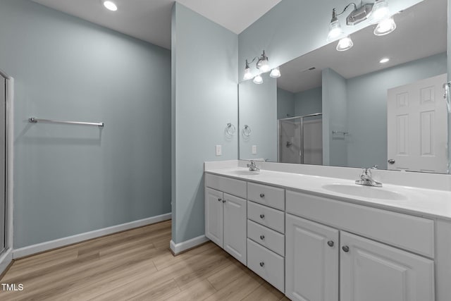 10133 Bessborough Dr, Raleigh, NC 27617 - bathroom featuring wood finished floors, a sink, double vanity, and a shower stall