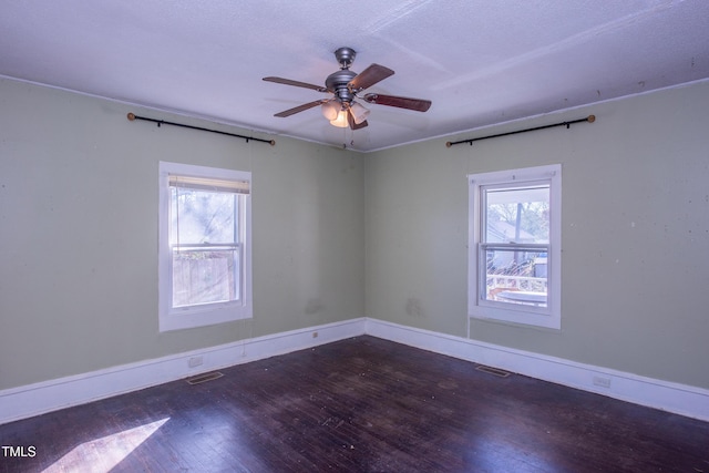 spare room featuring a ceiling fan, visible vents, baseboards, and hardwood / wood-style flooring