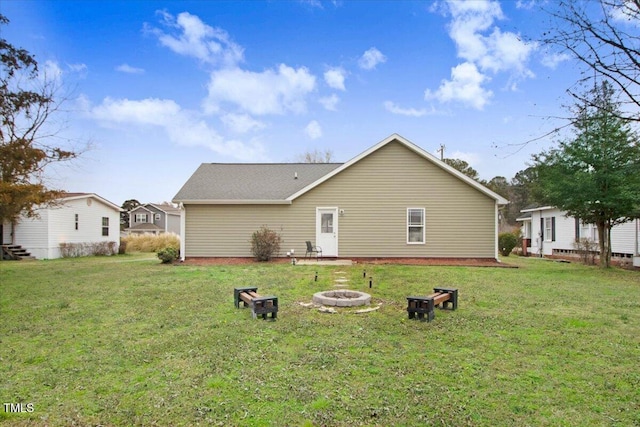 back of house with a yard and a fire pit