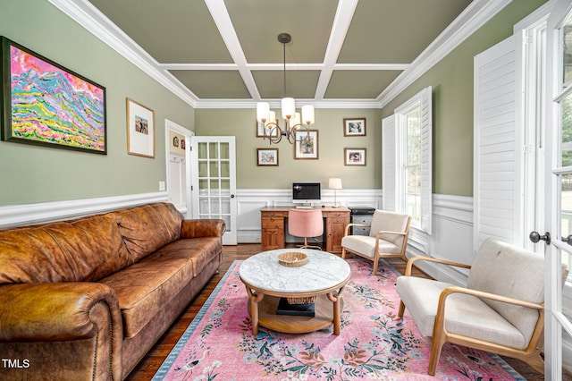 living room featuring ornamental molding, wainscoting, wood finished floors, a chandelier, and coffered ceiling