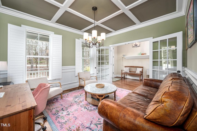 living room featuring crown molding, coffered ceiling, a notable chandelier, and wood finished floors