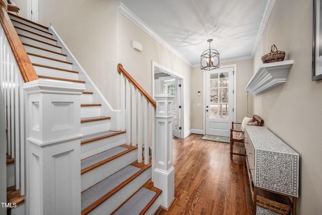 foyer with baseboards, ornamental molding, wood finished floors, an inviting chandelier, and stairs