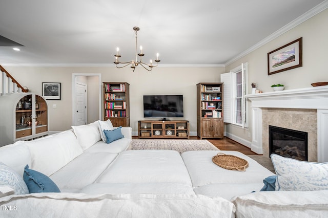 living room with a chandelier, a premium fireplace, wood finished floors, baseboards, and ornamental molding