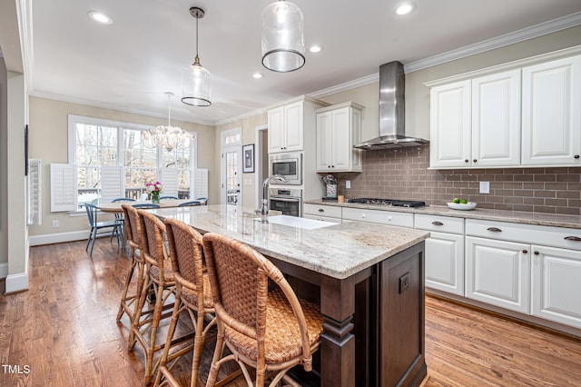 kitchen featuring wall chimney exhaust hood, ornamental molding, white cabinetry, and stainless steel appliances