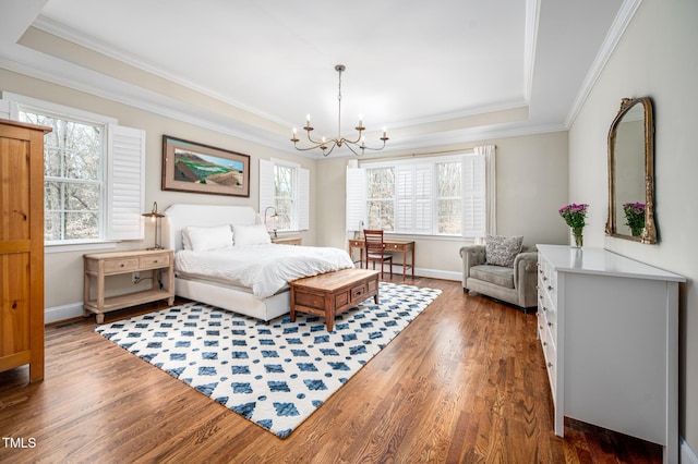 bedroom with wood finished floors, baseboards, ornamental molding, a tray ceiling, and an inviting chandelier