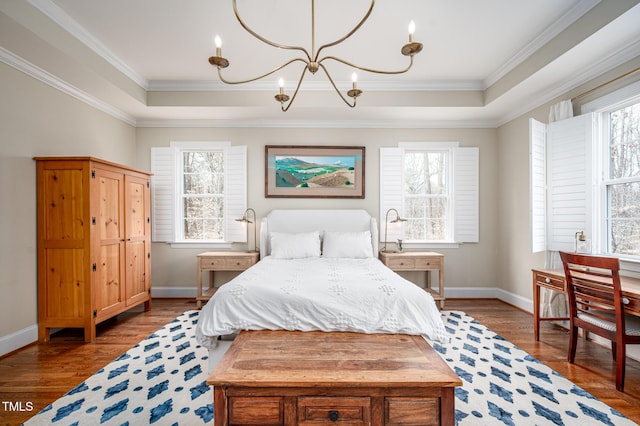 bedroom featuring ornamental molding, a tray ceiling, an inviting chandelier, and wood finished floors