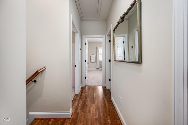 corridor featuring attic access, baseboards, and wood finished floors