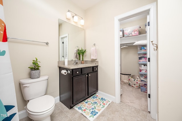 bathroom with baseboards, vanity, toilet, and tile patterned floors