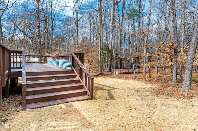 view of yard with a deck, stairway, and a trampoline