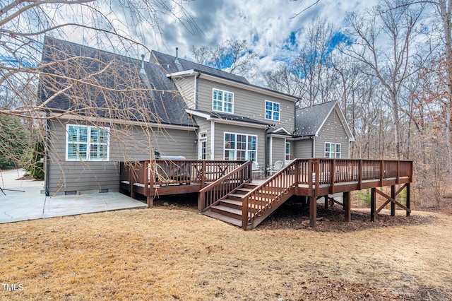 back of house with crawl space, a shingled roof, a wooden deck, and a patio