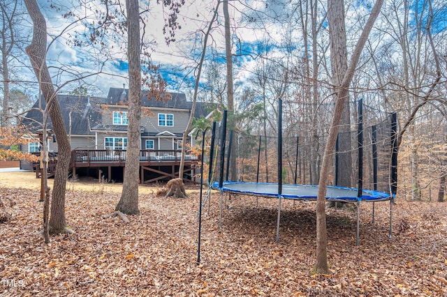 view of yard with a trampoline and a wooden deck