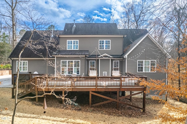 rear view of house featuring a wooden deck and roof with shingles