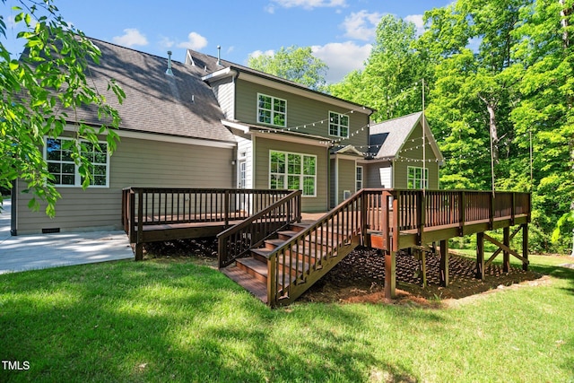 rear view of house with a deck, a shingled roof, and a lawn