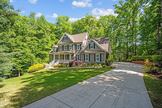 shingle-style home with a porch, a front lawn, and concrete driveway