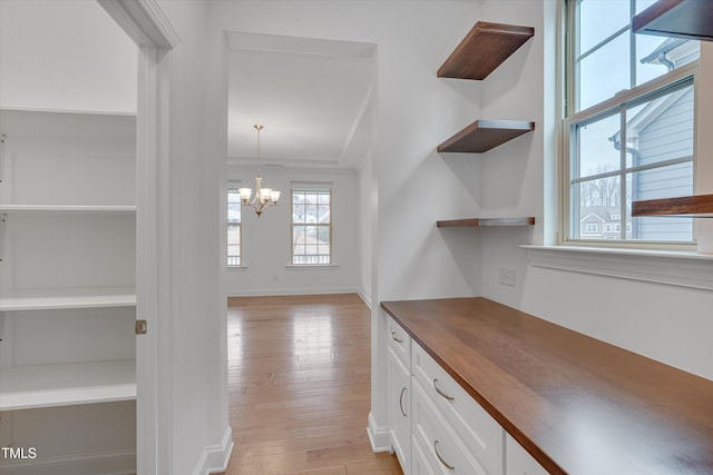 kitchen featuring open shelves, white cabinetry, an inviting chandelier, butcher block counters, and light wood finished floors