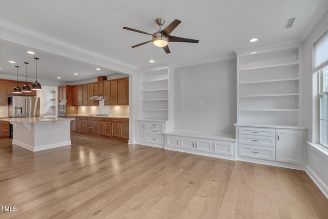 kitchen with a breakfast bar, light wood-style flooring, stainless steel appliances, under cabinet range hood, and brown cabinets