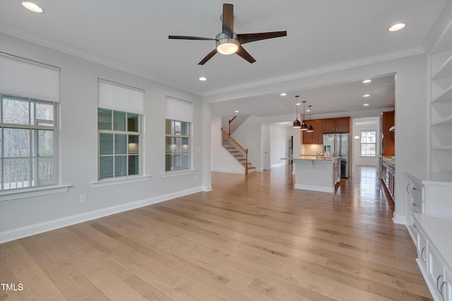 unfurnished living room featuring light wood-style flooring, stairs, baseboards, and ornamental molding