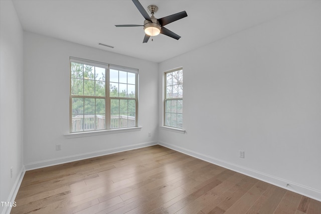 unfurnished room featuring visible vents, a ceiling fan, baseboards, and wood finished floors