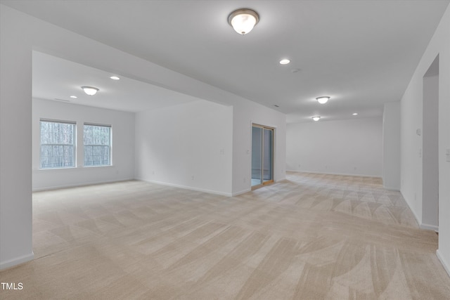 empty room featuring recessed lighting, light colored carpet, and baseboards