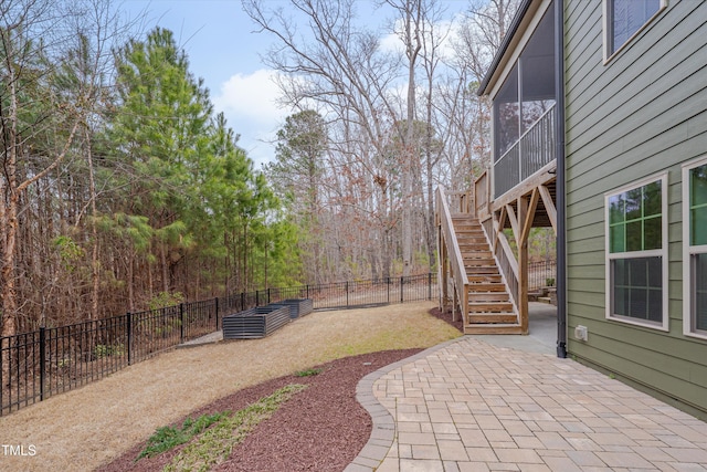 view of patio featuring stairs, fence private yard, and a sunroom